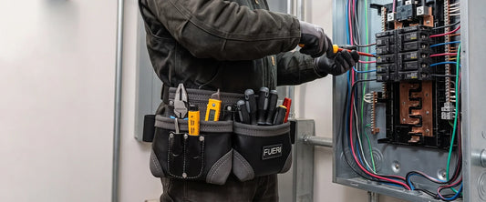Electrician wearing a FUERI tool belt while working on an electrical panel.